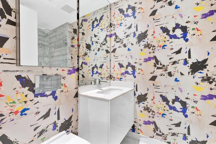 Designer Wall Covering ,Modern floating vanity with a white countertop and basin, wall-mounted chrome faucet, and expansive wall-to-wall mirror /guest bathrroom