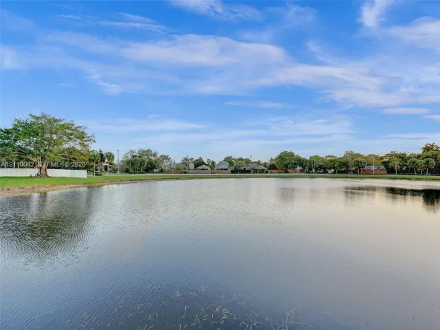 Waterfront lot featuring a wide expanse of open water, manicured grass perimeter, and mature trees