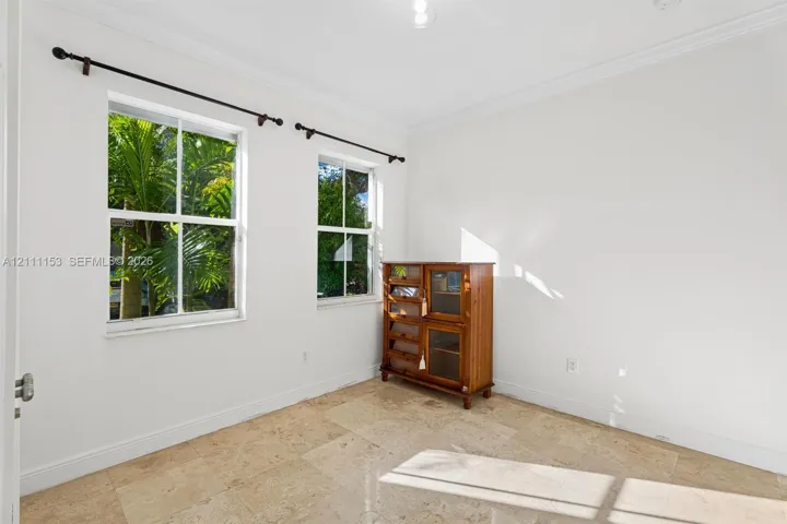 Natural stone flooring, double-hung windows, crown molding, and metal curtain rods