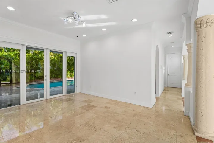 Interior space featuring polished stone flooring, recessed lighting, decorative columns, and floor-to-ceiling sliding glass doors with exterior pool exposure