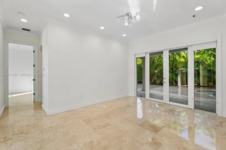 Neutral-toned stone tile flooring, multi-panel sliding glass doors, recessed lighting, and a multi-bulb modern ceiling light fixture