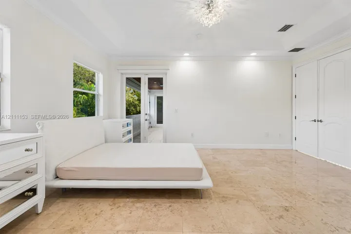 Tray ceiling featuring a decorative chandelier, polished stone flooring, and dual French doors
