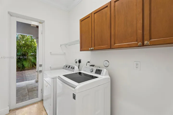 Laundry area featuring wood-finish cabinetry, stone flooring, and a glass-paneled exterior door