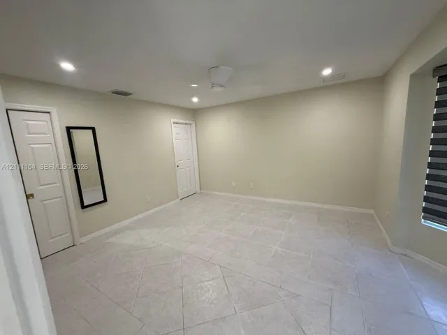 Neutral-toned interior featuring large-format ceramic tile flooring, recessed lighting, a ceiling fan, and multi-panel doors