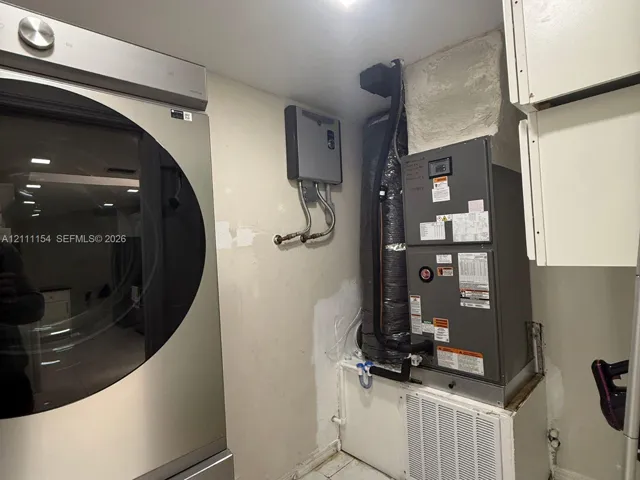 Dedicated utility space featuring a high-efficiency furnace, tankless water heater, and stainless steel laundry appliance