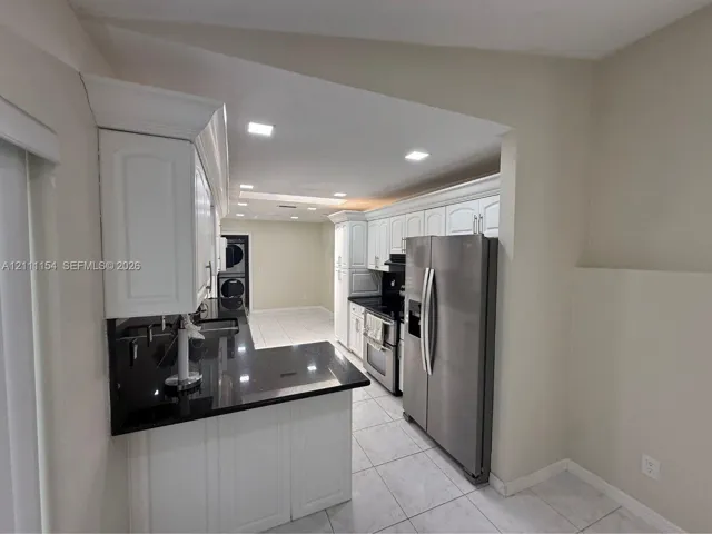 Kitchen featuring white cabinetry with crown molding, black countertops, stainless steel appliances, recessed lighting, and tile flooring