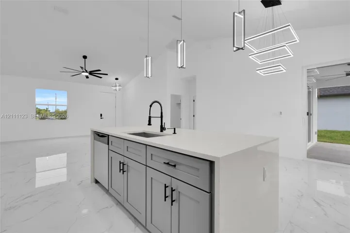 Kitchen island with sink and black faucet, open to the living area.