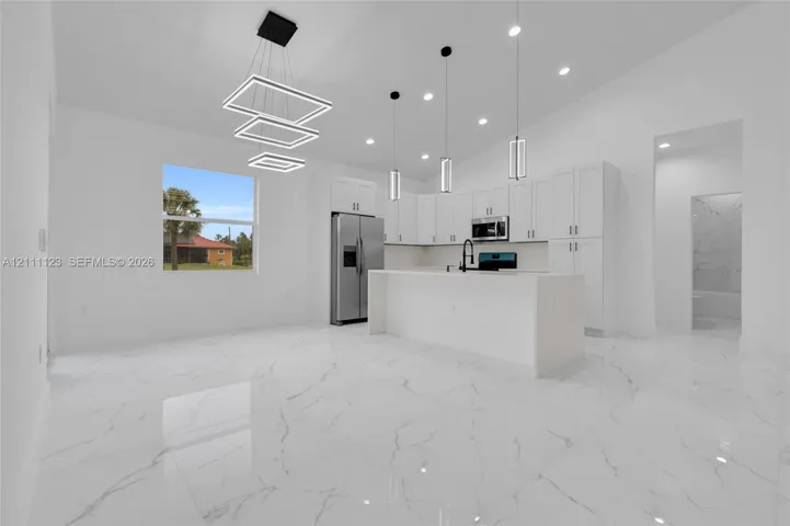 Dining area with modern light fixture, open to the kitchen island.