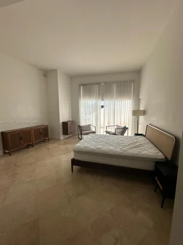 Room with stone tile flooring, high ceilings, and large glass sliding doors featuring floor-to-ceiling vertical blinds