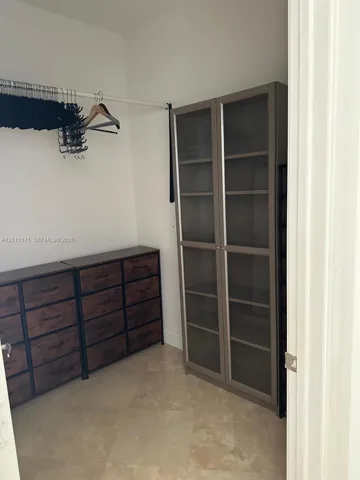 Storage space featuring tile flooring and a horizontal hanging rod