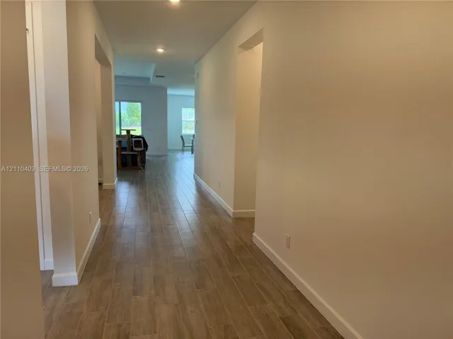 Interior hallway featuring wood-finish tile flooring, recessed lighting, and high ceilings