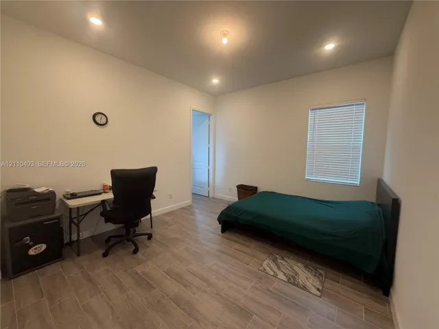 Room with wood-finish flooring, recessed lighting, and a window with integrated blinds