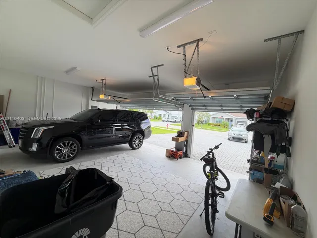 Two-car garage with patterned flooring, overhead lighting, and dual garage door openers