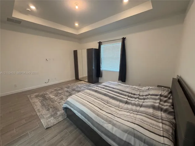 Tray ceiling with recessed lighting and wood-finish tile flooring