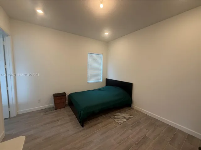 Room featuring neutral wall paint, wood-finish tile flooring, recessed lighting, and a window with blinds