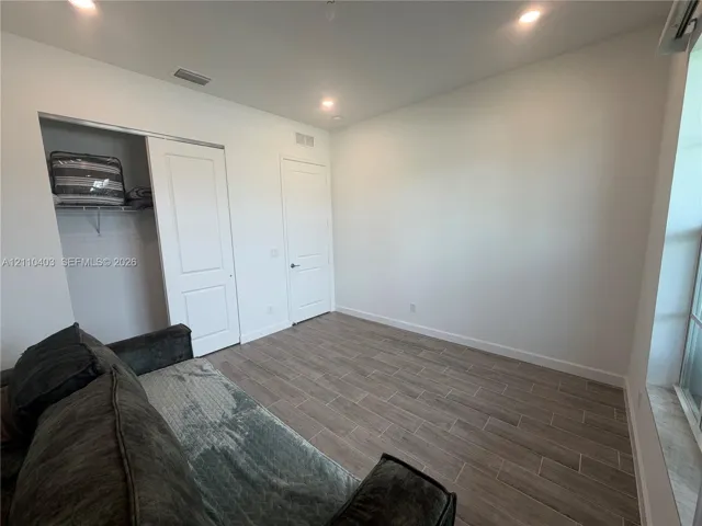 Room featuring wood-finish tile flooring, recessed lighting, a sliding closet door, and a multi-panel interior door