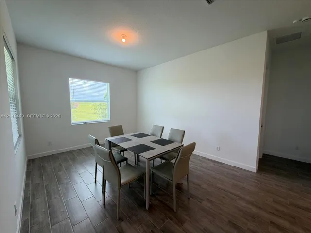 Room featuring neutral wall paint, wood-finish tile flooring, and dual windows with horizontal blinds