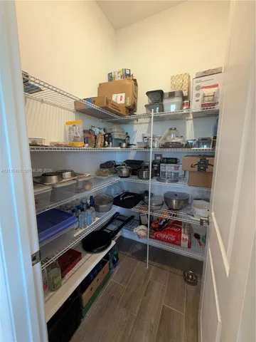 Walk-in storage pantry featuring multi-level wire shelving and wood-finish flooring