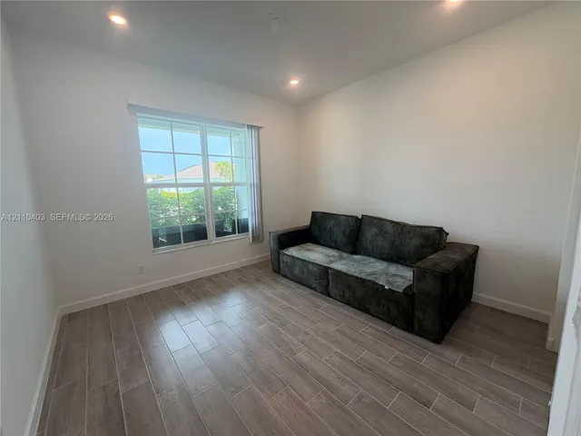 Neutral-toned room featuring wood-finish tile flooring, recessed ceiling lighting, and a multi-pane window