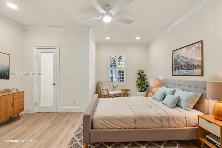 Neutral interior featuring wood-finish flooring, recessed lighting, crown molding, a ceiling fan, and a door with a frosted glass pane