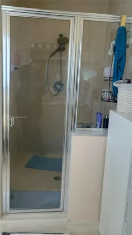 Shower enclosure featuring a chrome-framed glass door, wall-mounted showerhead, and tile surround