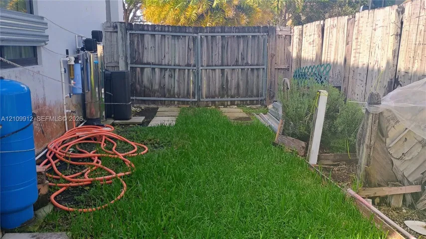 Outdoor area featuring a wood privacy fence, double-gate access, concrete paver path, and lawn space