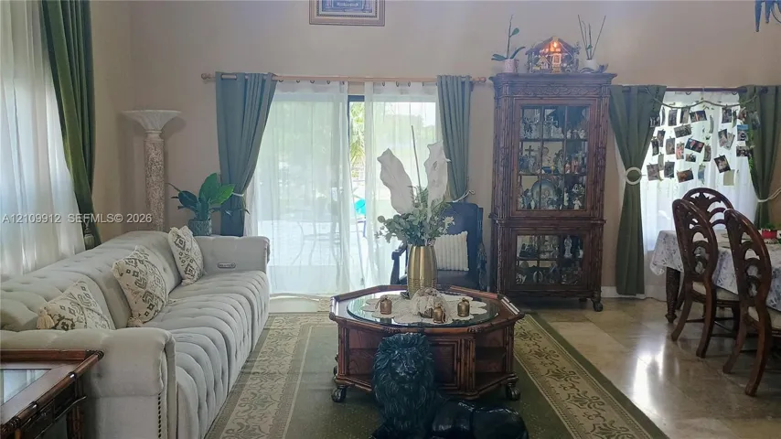 Living area featuring high ceilings, neutral stone-finish flooring, and sliding glass doors