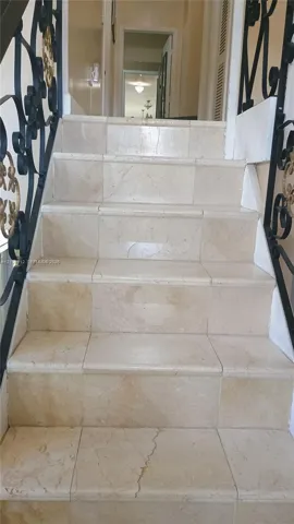 Staircase featuring stone-finish treads and risers with ornate black metal railings