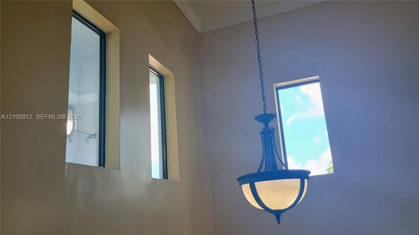 High-ceiling space featuring multiple tall rectangular windows and a tiered metal pendant light fixture with frosted glass shades