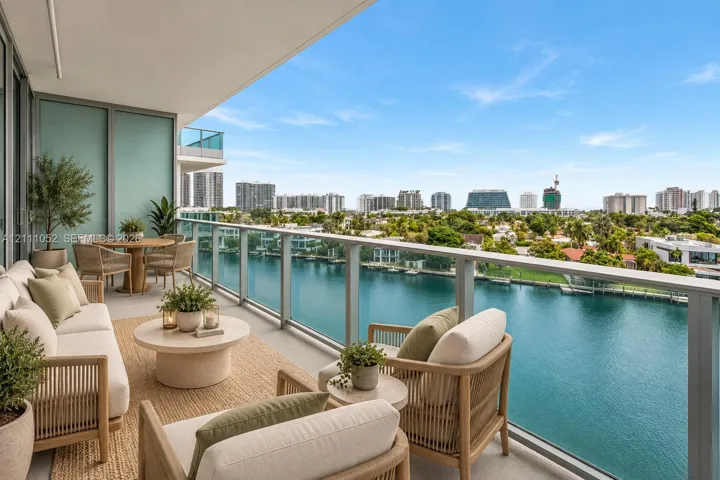 Covered outdoor terrace with glass panel railing, concrete flooring, and water frontage