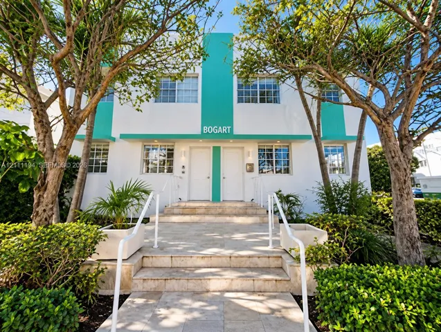 Art Deco-inspired exterior featuring dual-tone white and teal facade, stone-clad staircase, symmetrical entryways, and mature landscaping