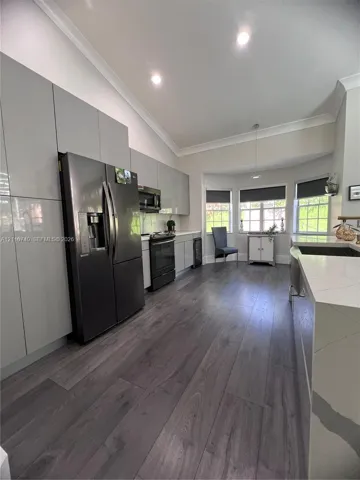 Modern kitchen featuring high-gloss cabinetry, wood-finish flooring, a quartz countertop island, recessed lighting, and a bay window