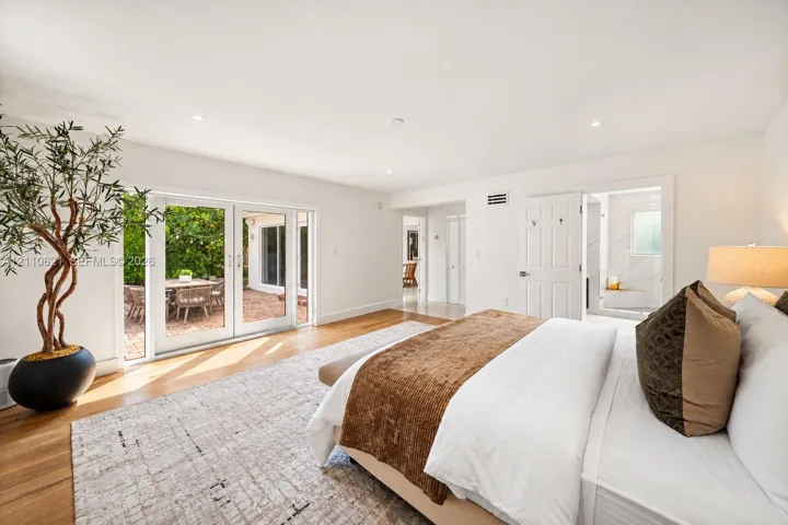 Spacious interior featuring wood-finish flooring, recessed lighting, and white glass-paned double doors opening to an exterior patio