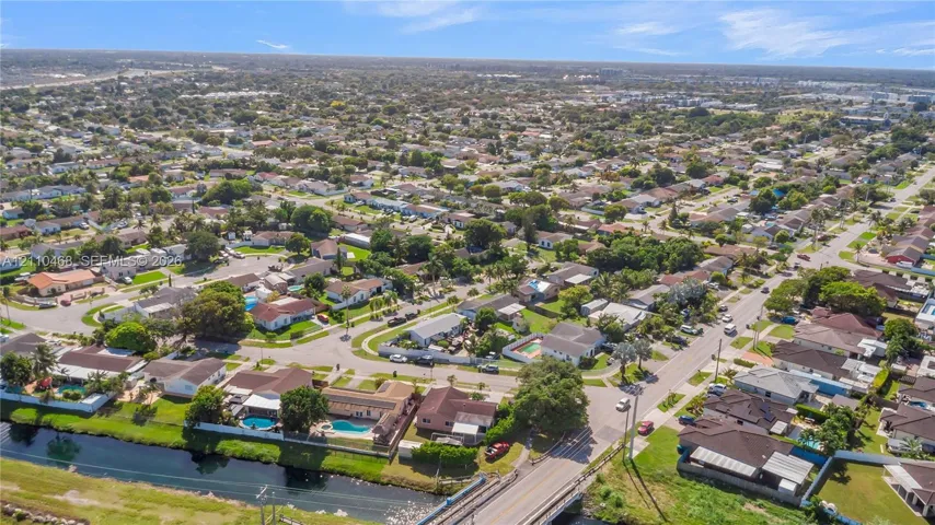 Aerial perspective of a suburban neighborhood featuring winding residential streets, established tree canopy, and waterfront lots