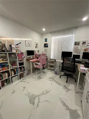Large-format tile flooring with a neutral veined pattern, recessed ceiling lighting, and built-in white shelving