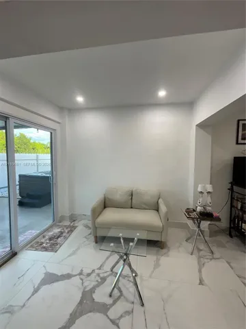 Large-format stone-style tile flooring with neutral veining, recessed ceiling lighting, and sliding glass door with external patio access