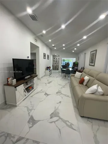 Large-format tile flooring with a veined pattern, recessed ceiling lighting, and smooth-finish walls