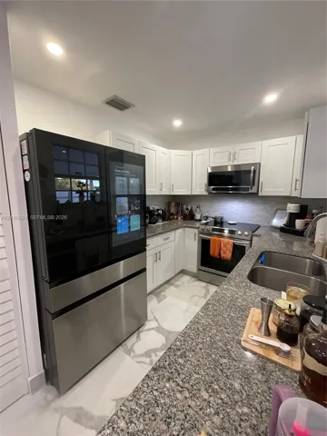 Kitchen featuring white shaker-style cabinetry, stone-finish countertops, stainless steel appliances, a multi-door smart refrigerator, and recessed lighting