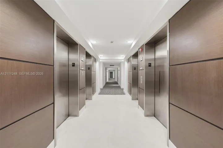 Elevator lobby featuring metallic doors, wood-paneled walls, and recessed ceiling lighting