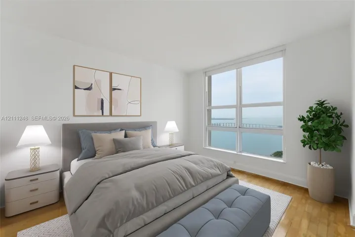 Floor-to-ceiling windows featuring water and bridge scenery, wood-finish flooring, and neutral wall color