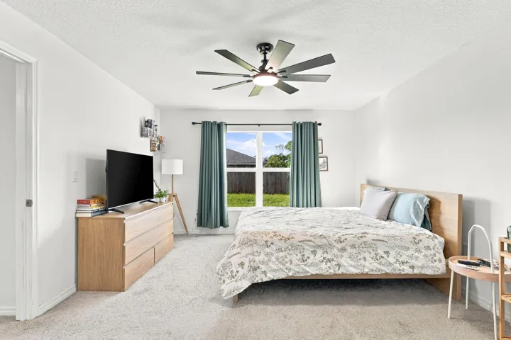 Comfortable bedroom with ceiling fan and natural light.