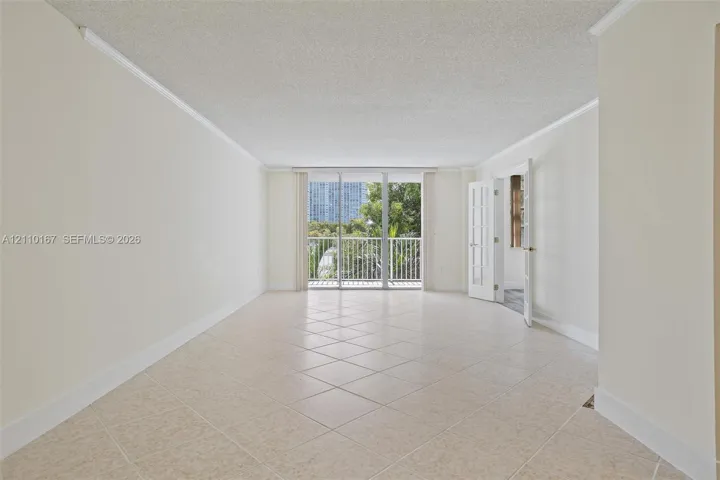Neutral-toned ceramic tile flooring, crown molding, sliding glass doors, and French-style doors