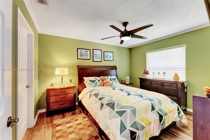 Bedroom featuring wood-finish flooring, a multi-blade ceiling fan with integrated lighting, and horizontal window blinds