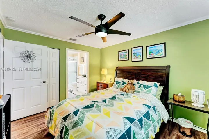 Bedroom featuring wood-finish flooring, a centrally mounted ceiling fan with integrated lighting, and a six-panel interior door
