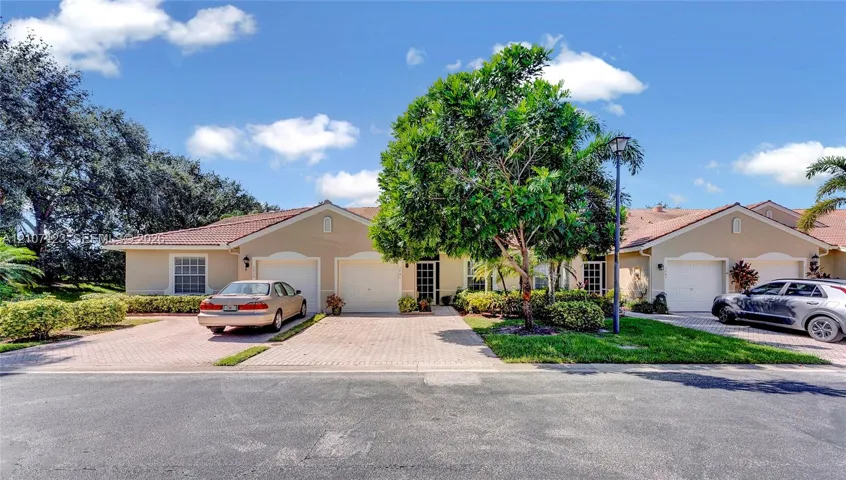 Single-story residence featuring a tile roof, dual-bay garages with paneled doors, and paved driveways
