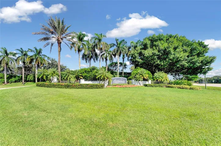 Expansive landscaped grounds featuring mature palms, manicured hedging, ornamental flower beds, and substantial shade trees