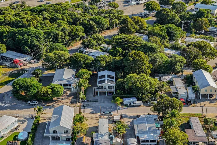 Aerial perspective of a multi-level structure featuring a pitched roof, integrated solar panels, and an elevated deck