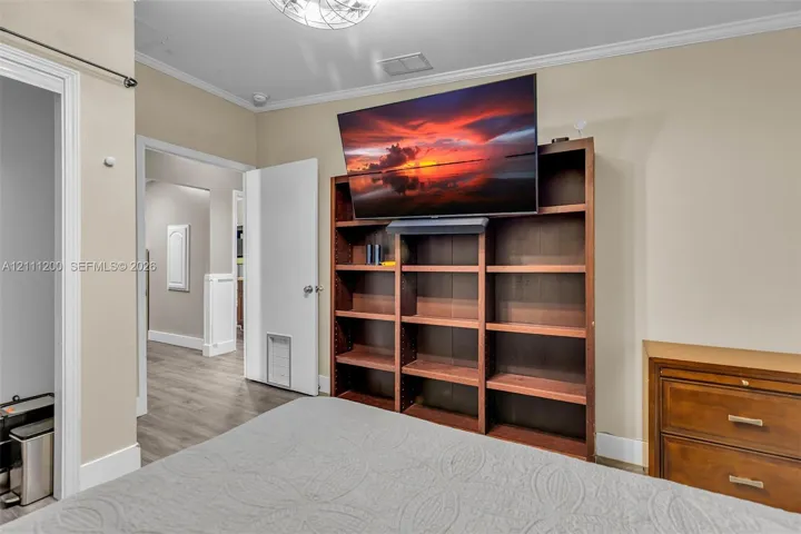 Built-in floor-to-ceiling wood shelving unit, neutral wall finishes, wood-finish flooring, and recessed ceiling lighting