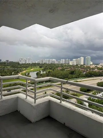 Covered balcony featuring white metal railings and concrete flooring