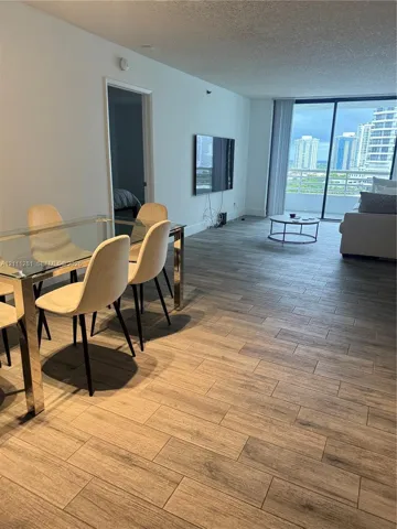 Open-concept interior featuring porcelain-finish flooring, floor-to-ceiling glass sliding doors, and a private balcony